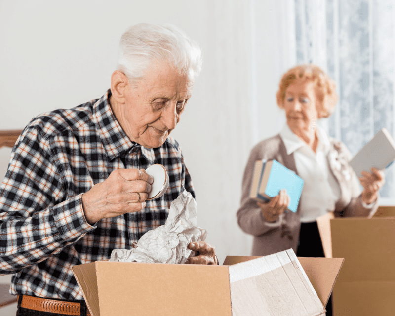 an elderly couple packing their moving boxes